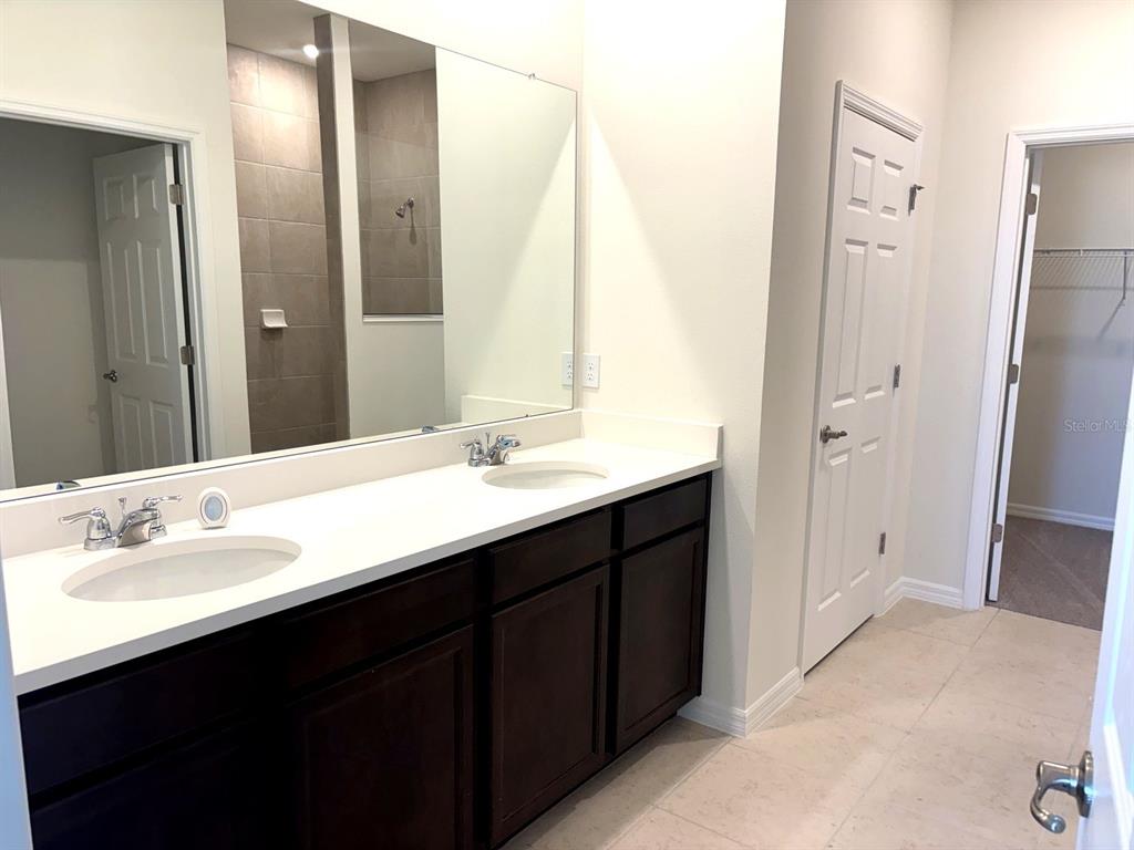 A bathroom features a double vanity with dark cabinets, white countertops, and a large mirror — 2363 SELENIA STREET, LAKE ALFRED, FL
