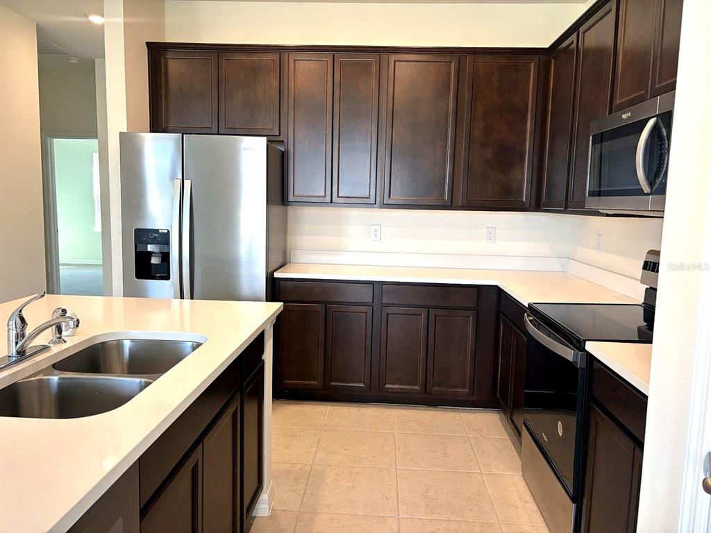 A kitchen featuring dark wood cabinets, stainless steel appliances, and white countertops — 2363 SELENIA STREET, LAKE ALFRED, FL