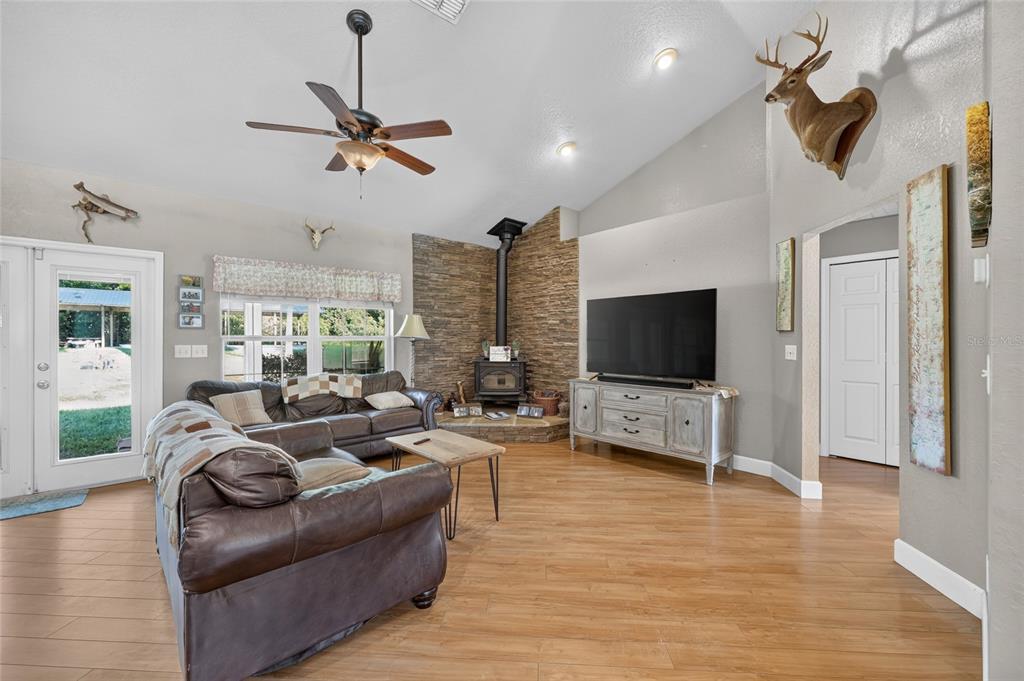 A living room features wood-look flooring, a corner stone fireplace, and a mounted deer head — 13930 NE 41ST TERRACE, ANTHONY, FL