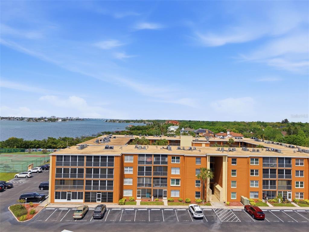 An aerial view of a multi-story orange apartment building with a parking lot and water — 12760 INDIAN ROCKS ROAD UNIT 1065, LARGO, FL