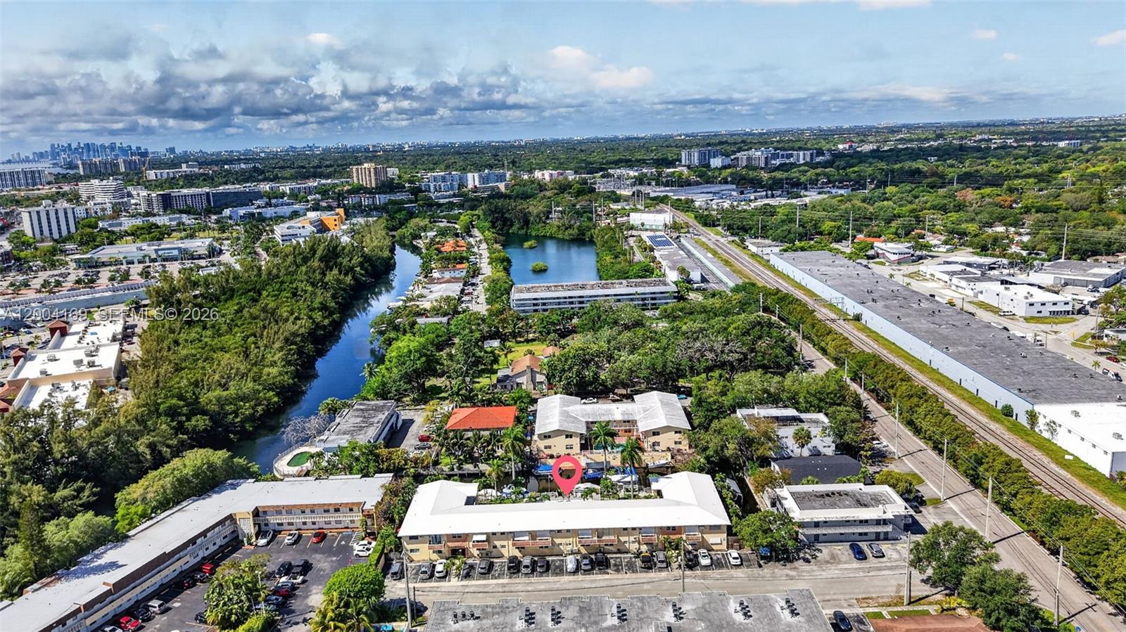 An aerial view shows a multi-story apartment complex with a parking lot and pool — 1820 Venice Park Dr # 102, North Miami FL 33181, NORTH MIAMI, FL