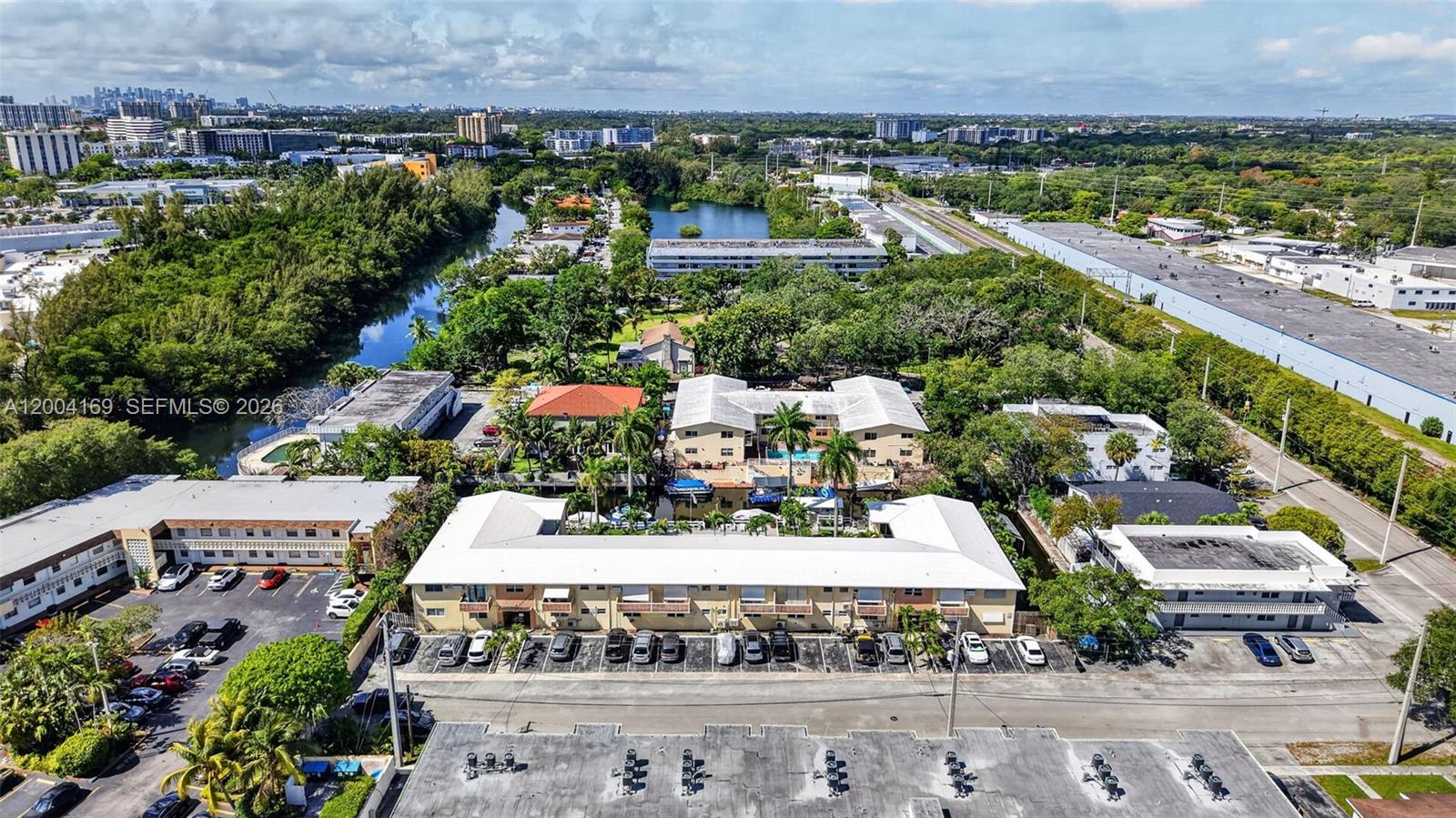 An aerial view shows a multi-story apartment complex with a parking lot and surrounding greenery — 1820 Venice Park Dr # 102, North Miami FL 33181, NORTH MIAMI, FL