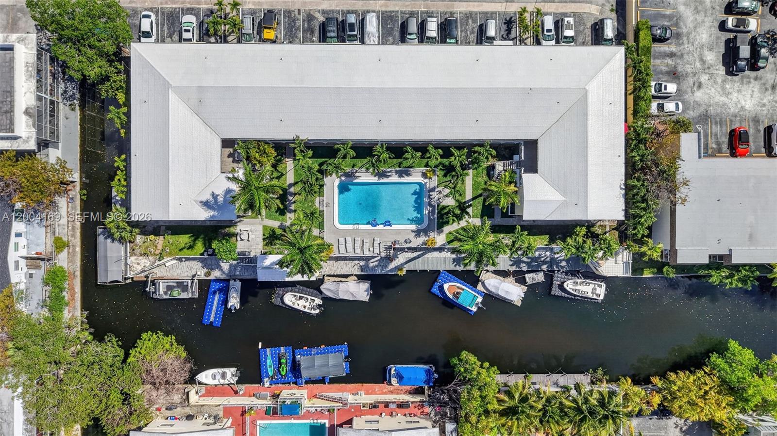 An aerial view shows a multi-unit building with a central pool and boat docks — 1820 Venice Park Dr # 102, North Miami FL 33181, NORTH MIAMI, FL
