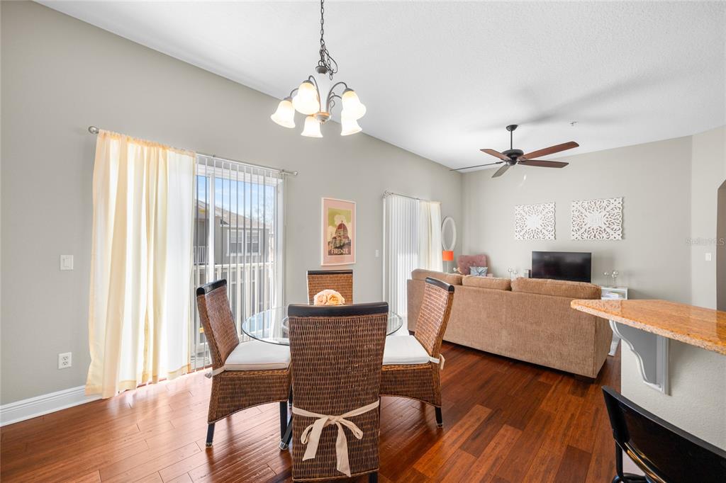 A dining area with a glass table and wicker chairs sits beside a living room — 10235 CALA LILY TRAIL UNIT 35A, ORLANDO, FL