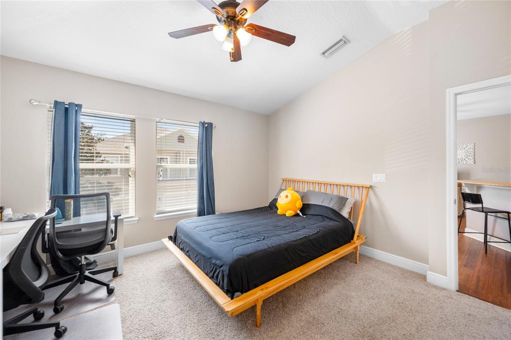 A bedroom features a wooden bed frame, a desk with a chair, and two windows — 10235 CALA LILY TRAIL UNIT 35A, ORLANDO, FL