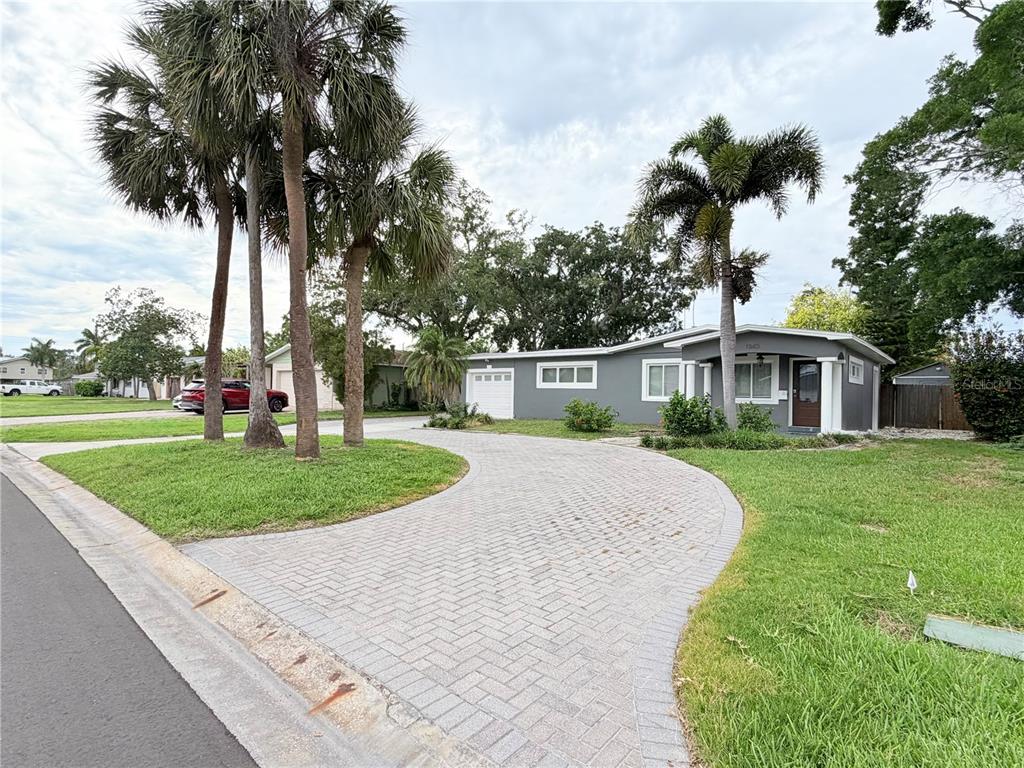 A gray single-story house features a paved circular driveway and several tall palm trees — 1843 OKLAHOMA AVENUE NE, ST PETERSBURG, FL