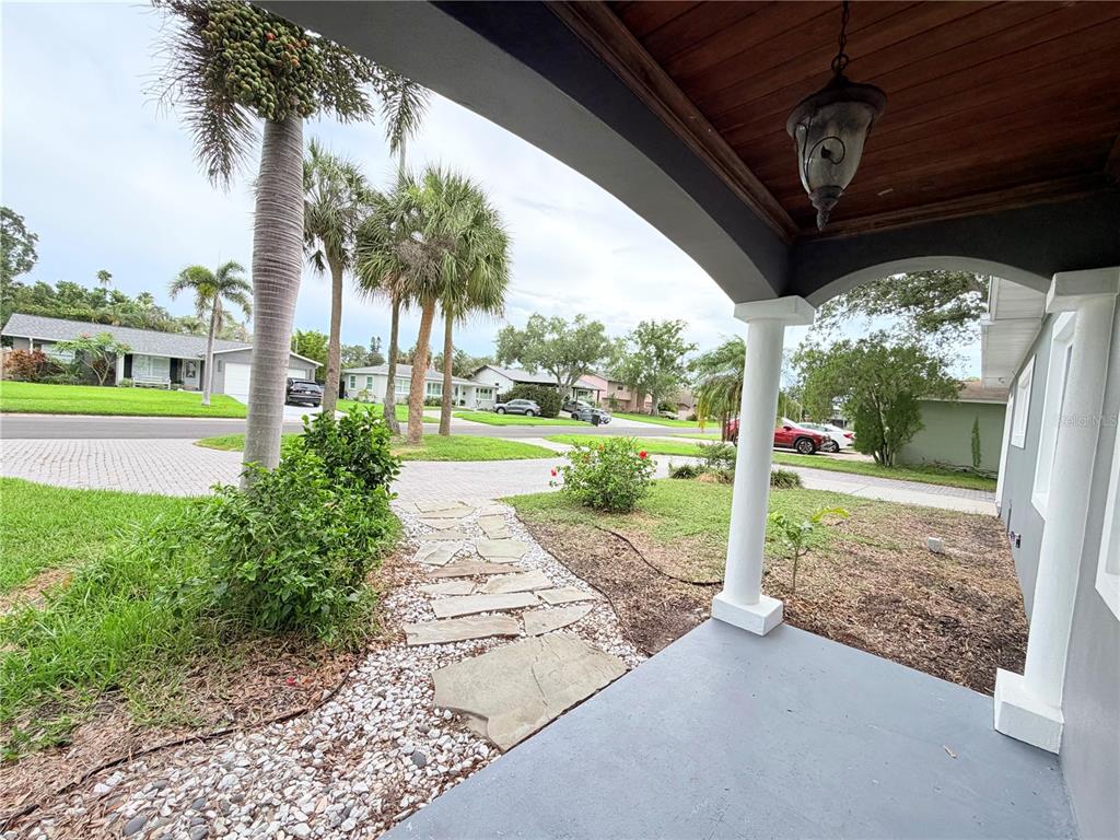 A view from a covered porch looking out toward a residential street with palm trees — 1843 OKLAHOMA AVENUE NE, ST PETERSBURG, FL