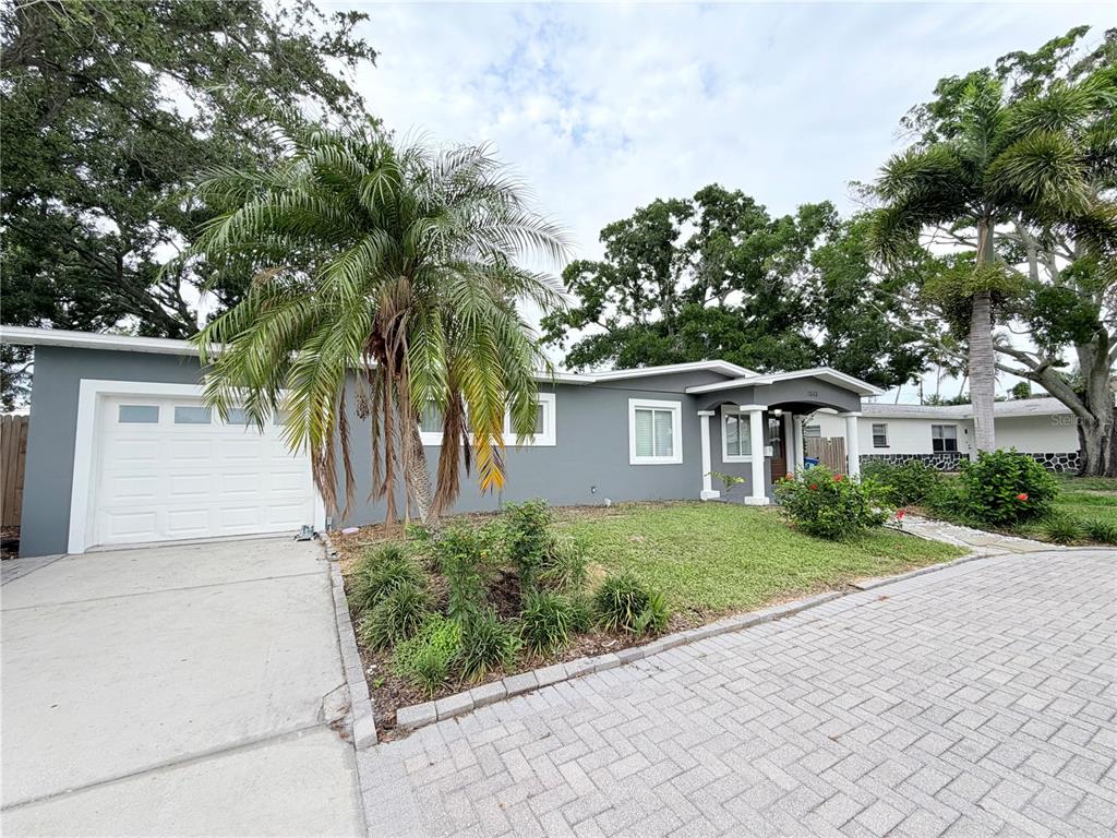 A gray single-story house with a white garage door, palm tree, and paved driveway — 1843 OKLAHOMA AVENUE NE, ST PETERSBURG, FL
