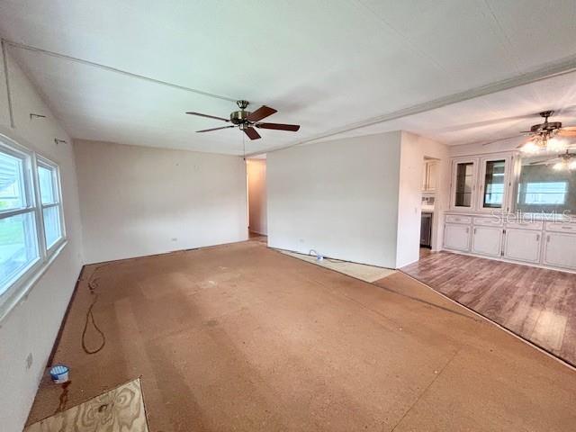An unfinished living room features exposed subflooring, a ceiling fan, and an adjacent dining area — 427 HAWTHORNE BOULEVARD, LEESBURG, FL