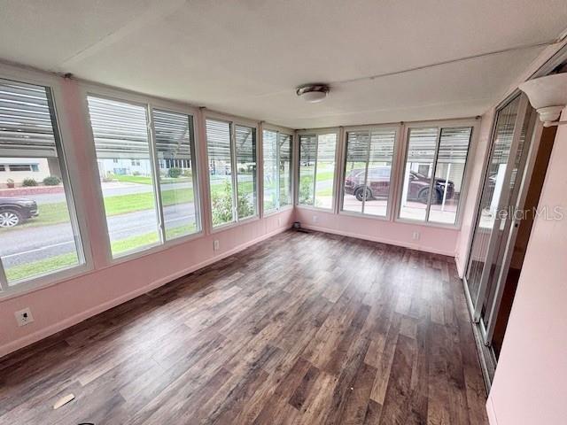 A sunroom features wood-look flooring, pink walls, and large windows overlooking a residential street — 427 HAWTHORNE BOULEVARD, LEESBURG, FL
