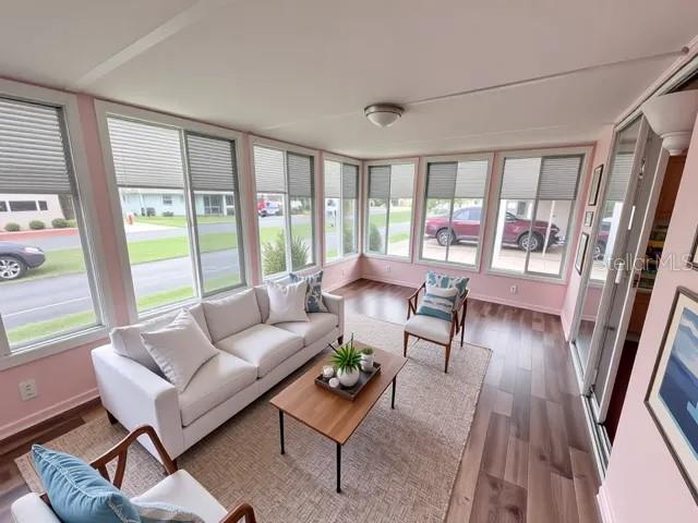 A sunroom features light pink walls, large windows, a white sofa, and wood-look flooring — 427 HAWTHORNE BOULEVARD, LEESBURG, FL