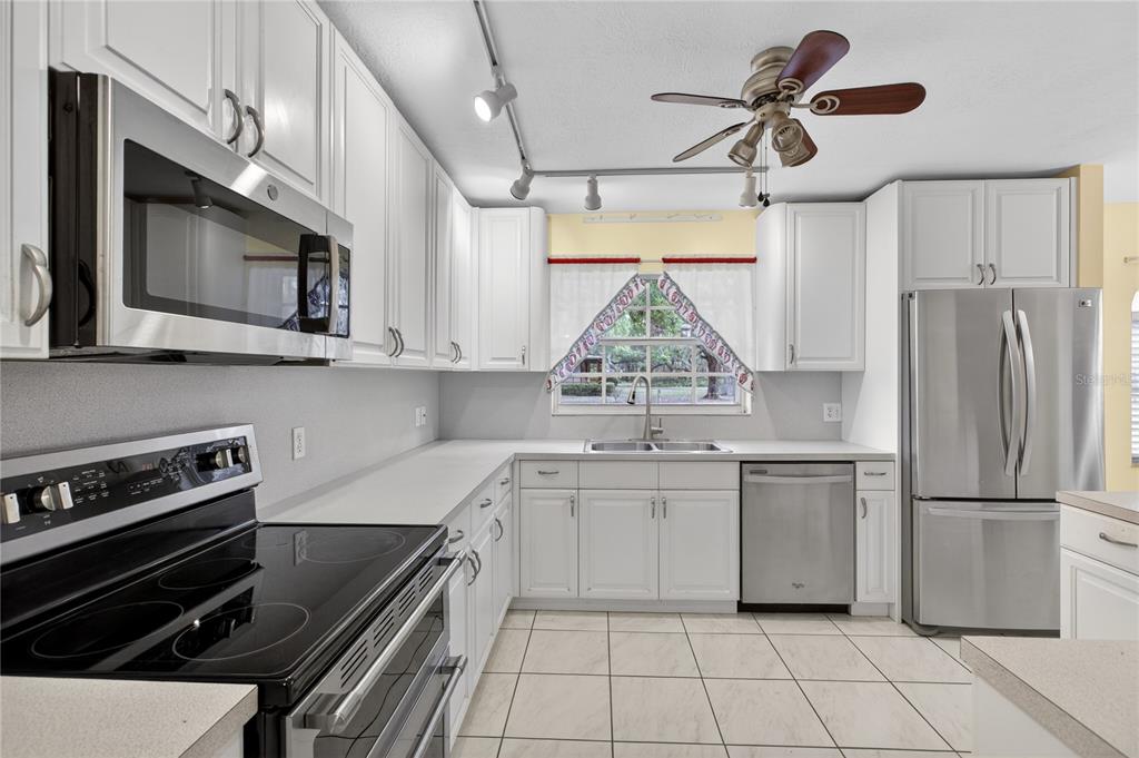 A kitchen with white cabinets, stainless steel appliances, light countertops, and tile flooring — 2065 OAK BEACH BOULEVARD, SEBRING, FL