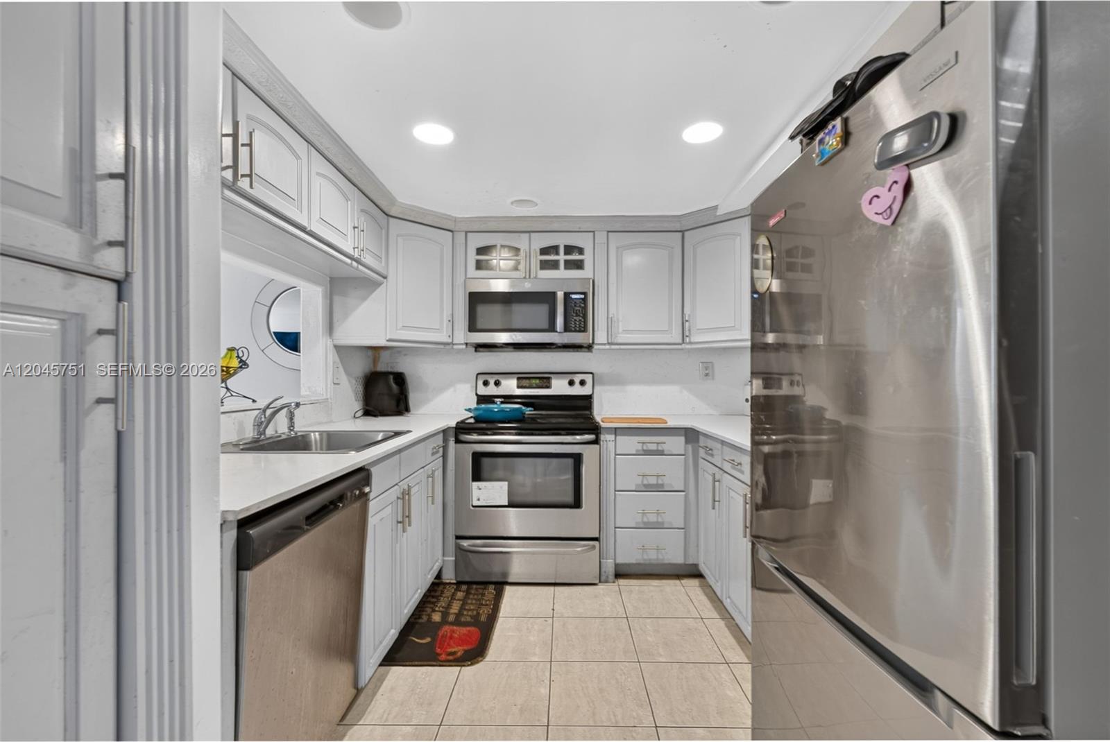 A galley kitchen features stainless steel appliances, light gray cabinetry, and tiled flooring — 20065 NE 3rd Ct # 5, Miami FL 33179, MIAMI, FL