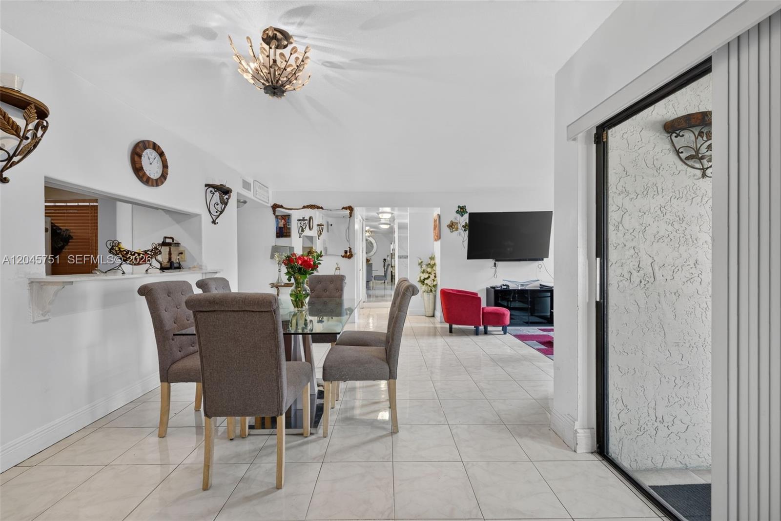 A dining area with a glass table and gray chairs leads into a living room — 20065 NE 3rd Ct # 5, Miami FL 33179, MIAMI, FL