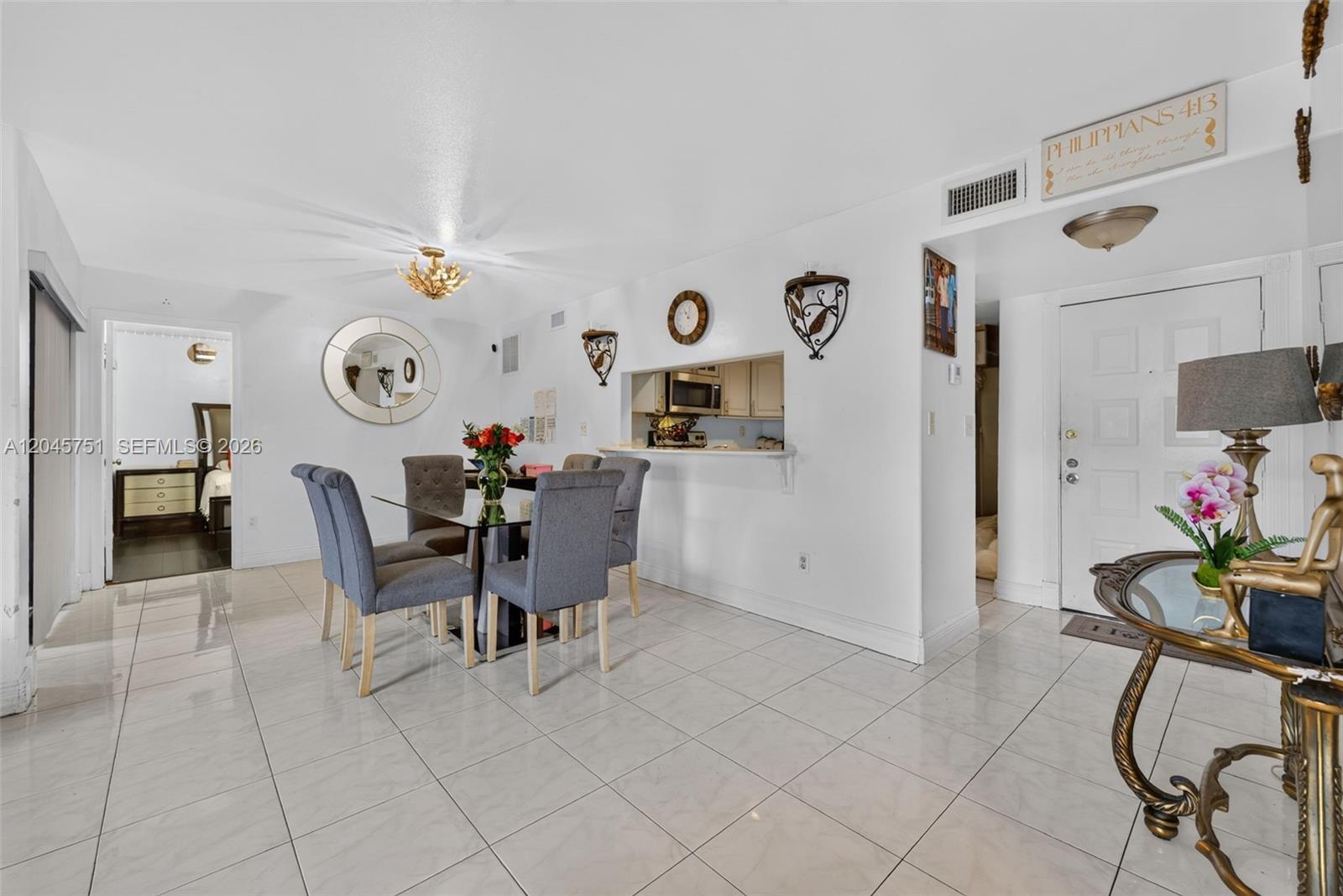 A dining area with a glass table, gray chairs, and tile flooring opens to a kitchen — 20065 NE 3rd Ct # 5, Miami FL 33179, MIAMI, FL