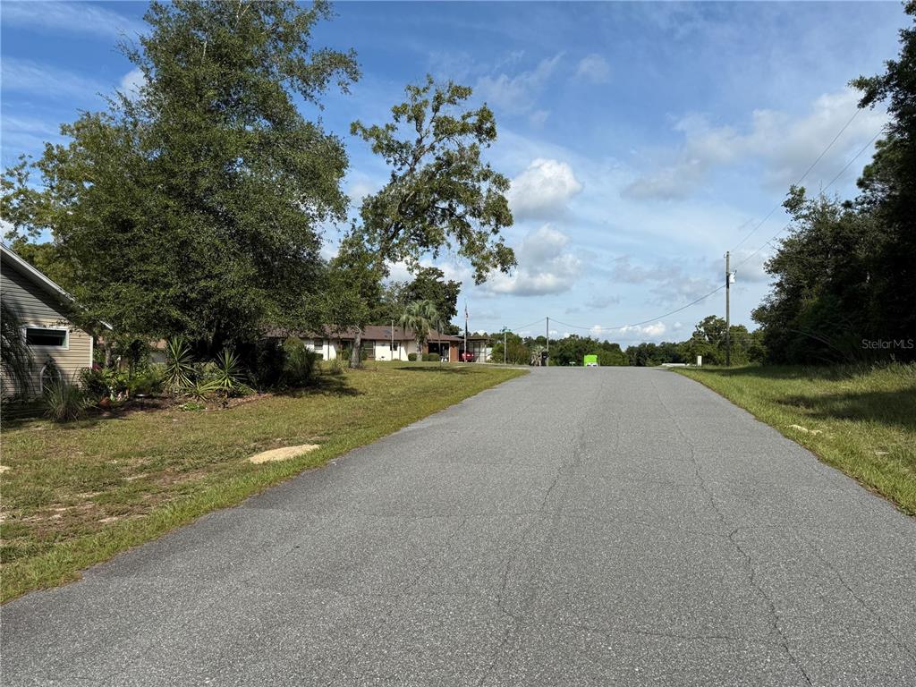 A paved road leads uphill toward a residential house surrounded by trees and grass — 9339 N MILAM WAY, CITRUS SPRINGS, FL