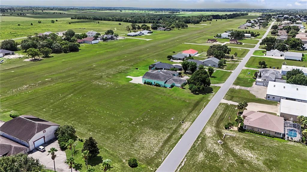 An aerial view shows a large, grassy vacant lot adjacent to a light green house — 8491 SE 72ND AVENUE, OCALA, FL