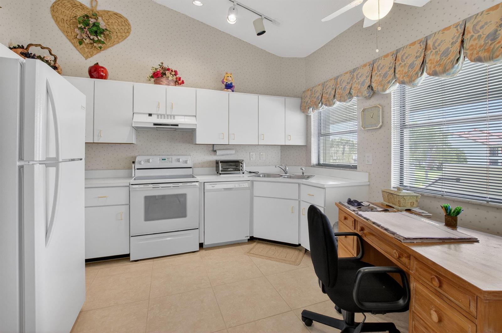 A kitchen features white cabinets, white appliances, tile flooring, and a wooden desk area — 5907 Parkwalk Drive, Boynton Beach FL 33472, BOYNTON BEACH, FL