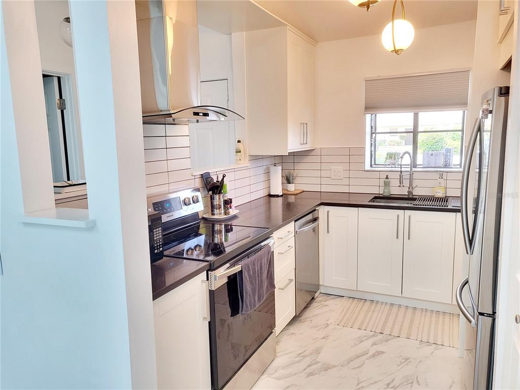 A kitchen features white cabinets, dark countertops, stainless steel appliances, and white subway tile backsplashes — 2903 63RD STREET W, BRADENTON, FL