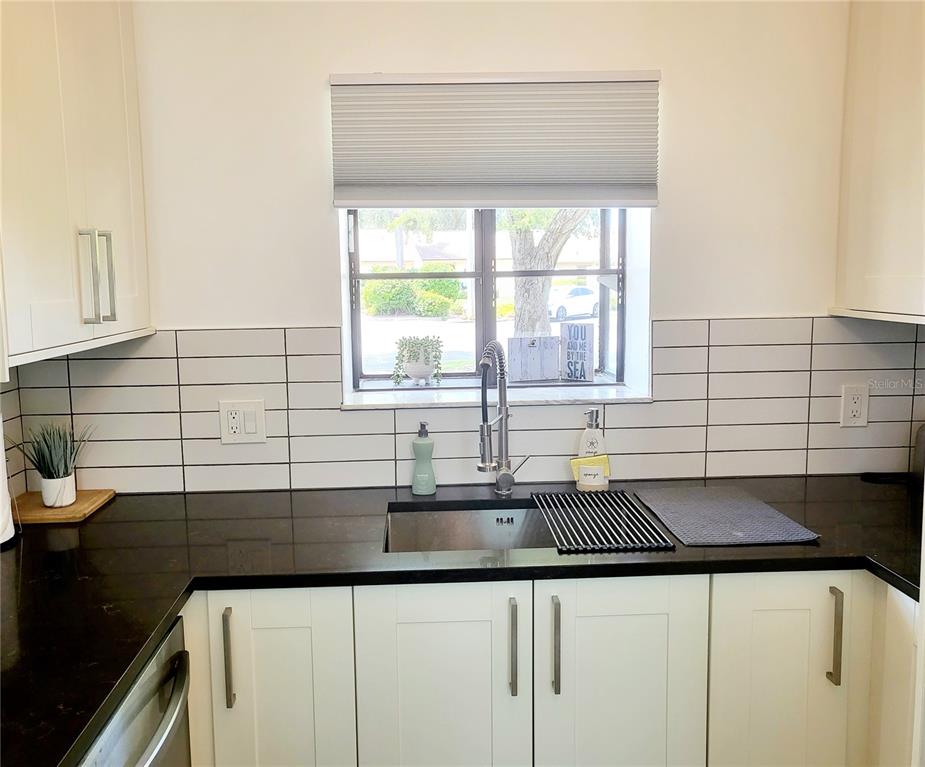 A kitchen sink area features white cabinets, black countertops, and a white subway tile backsplash — 2903 63RD STREET W, BRADENTON, FL