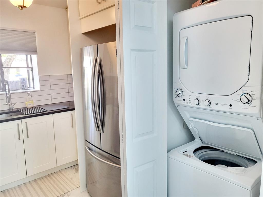 A kitchen features white cabinets, a stainless steel refrigerator, and a stacked laundry unit — 2903 63RD STREET W, BRADENTON, FL