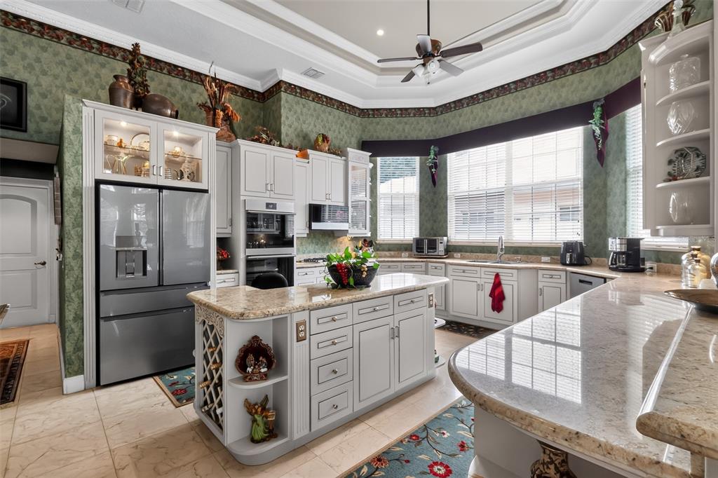 A kitchen with light gray cabinets, granite countertops, a central island, and green wallpaper — 7957 S PARK PLACE, ORLANDO, FL