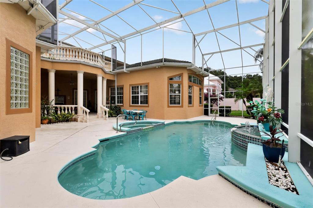 A screened-in pool area features a swimming pool, a hot tub, and a tan house — 7957 S PARK PLACE, ORLANDO, FL