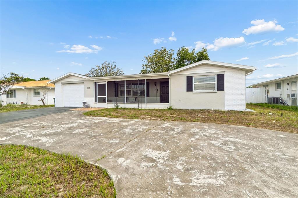 A single-story house with a white brick exterior, a screened-in porch, and a concrete driveway — 5915 OTIS DRIVE, NEW PORT RICHEY, FL
