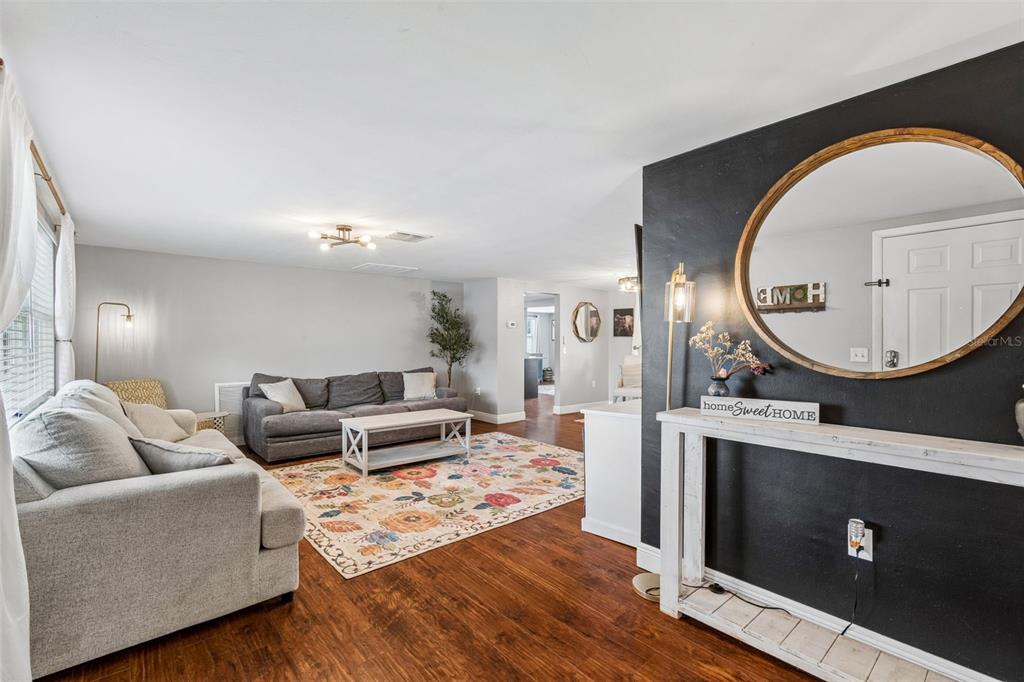 A living room features a gray sofa, a floral rug, and a black accent wall — 5915 OTIS DRIVE, NEW PORT RICHEY, FL
