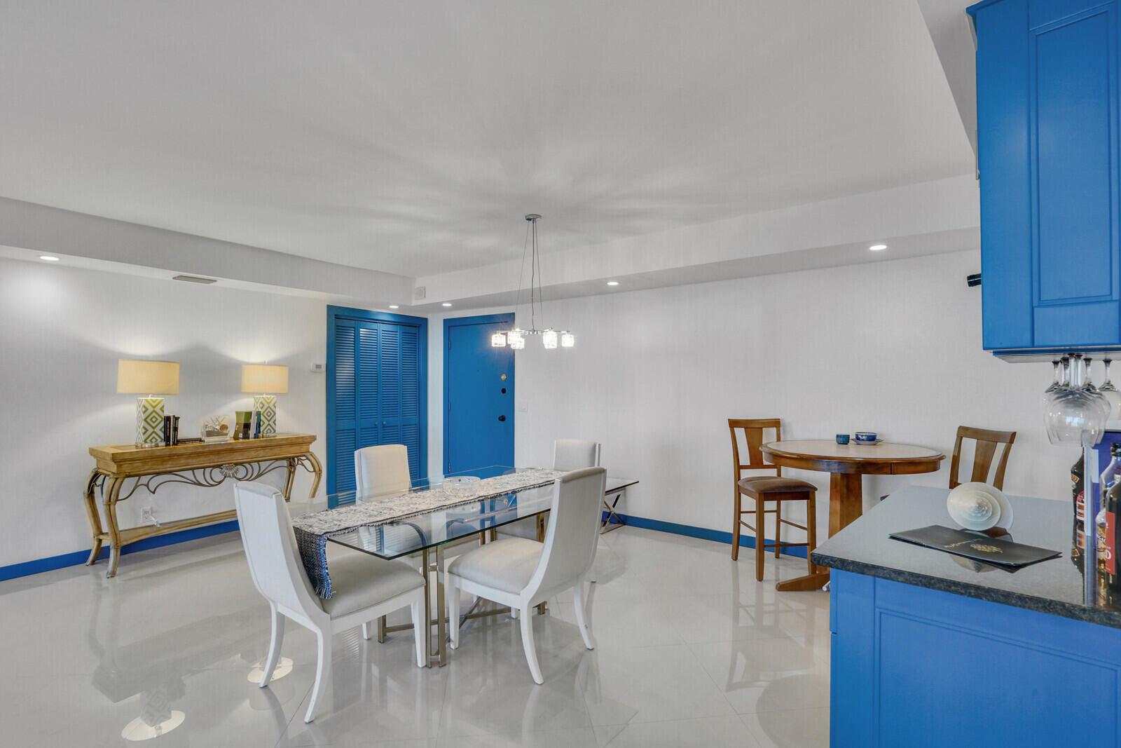 A dining area features a glass table, white chairs, blue cabinets, and a blue door — 2295 S Ocean Boulevard # 619, Palm Beach FL 33480, PALM BEACH, FL