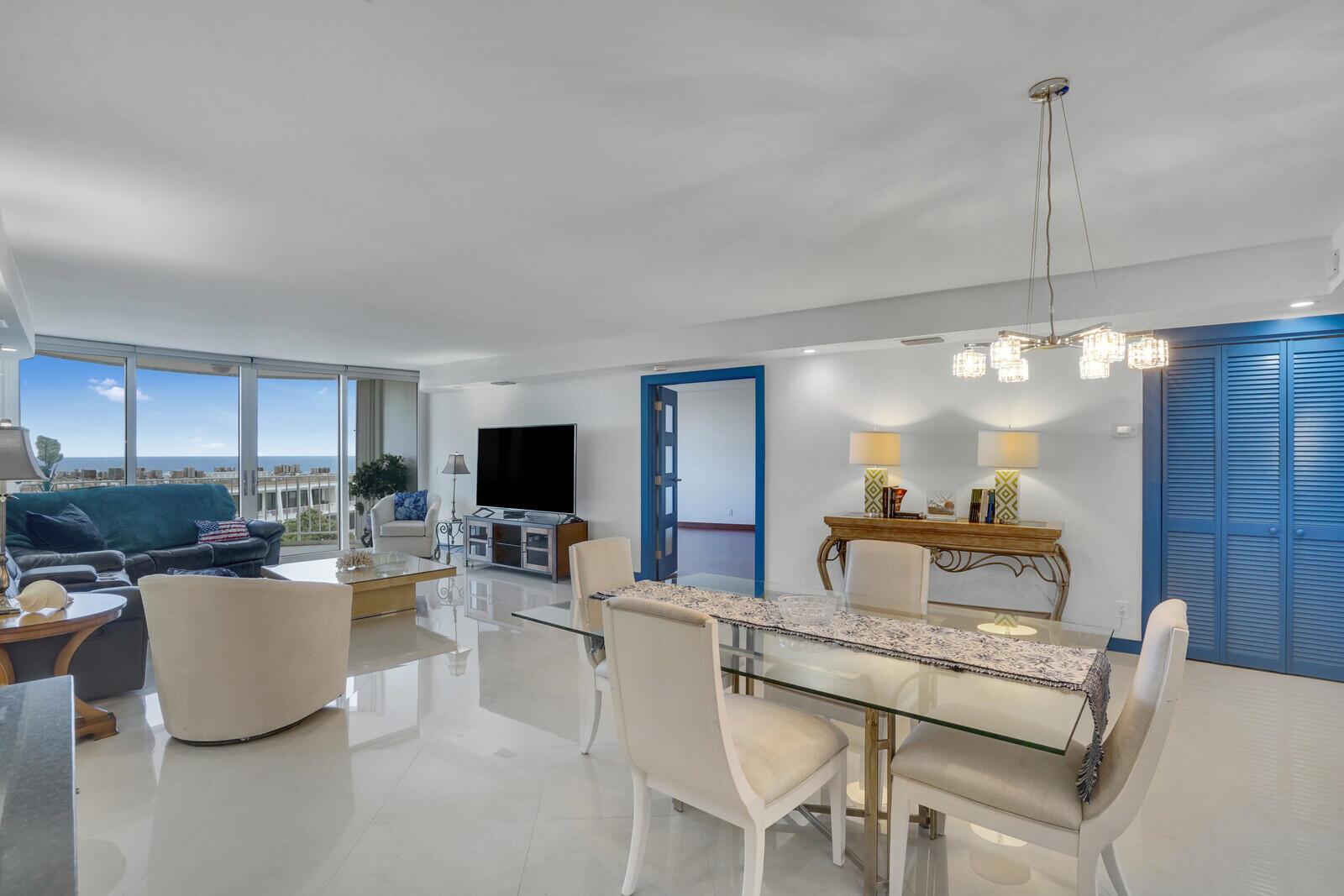 A bright living and dining area with white tile floors, blue accents, and ocean views — 2295 S Ocean Boulevard # 619, Palm Beach FL 33480, PALM BEACH, FL