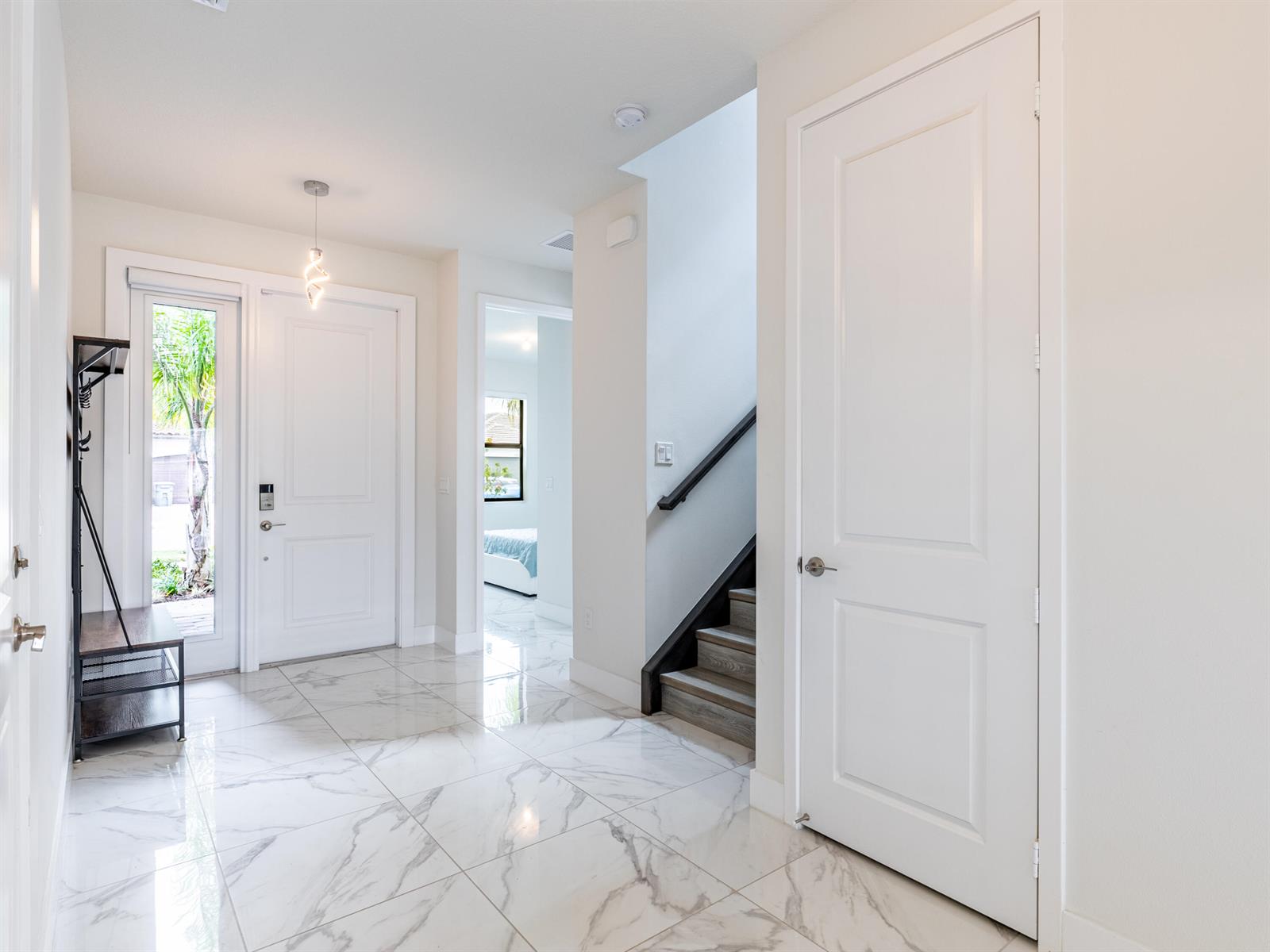 An entryway features white marble-look tile flooring, a coat rack, and a staircase with wood steps — 7191 Montereal Path, Lake Worth FL 33463, LAKE WORTH, FL