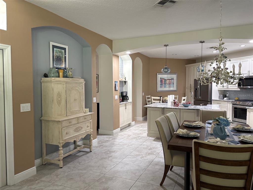 A dining area and kitchen feature tile flooring, neutral walls, and a decorative hutch — 30335 LETTINGWELL CIRCLE, WESLEY CHAPEL, FL
