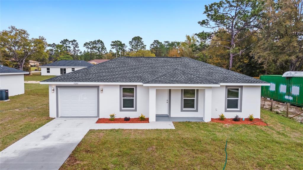 A single-story white house with a gray shingled roof and a one-car garage — 13771 SW 104TH STREET, DUNNELLON, FL