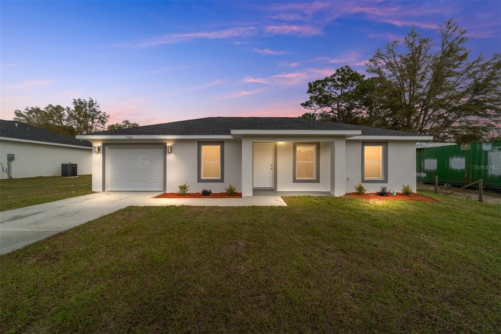 An empty room with gray walls, wood-look flooring, vaulted ceilings, and a sliding glass door — 13771 SW 104TH STREET, DUNNELLON, FL
