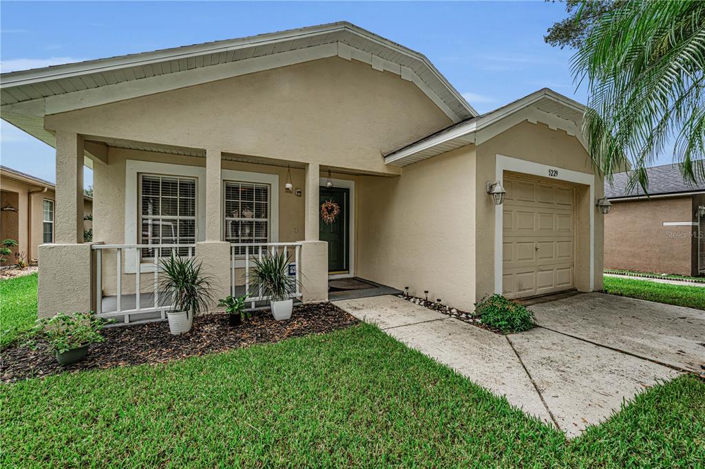 A single-story house with a beige stucco exterior, a front porch, and a one-car garage — 5229 MANGO FRUIT STREET, SEFFNER, FL