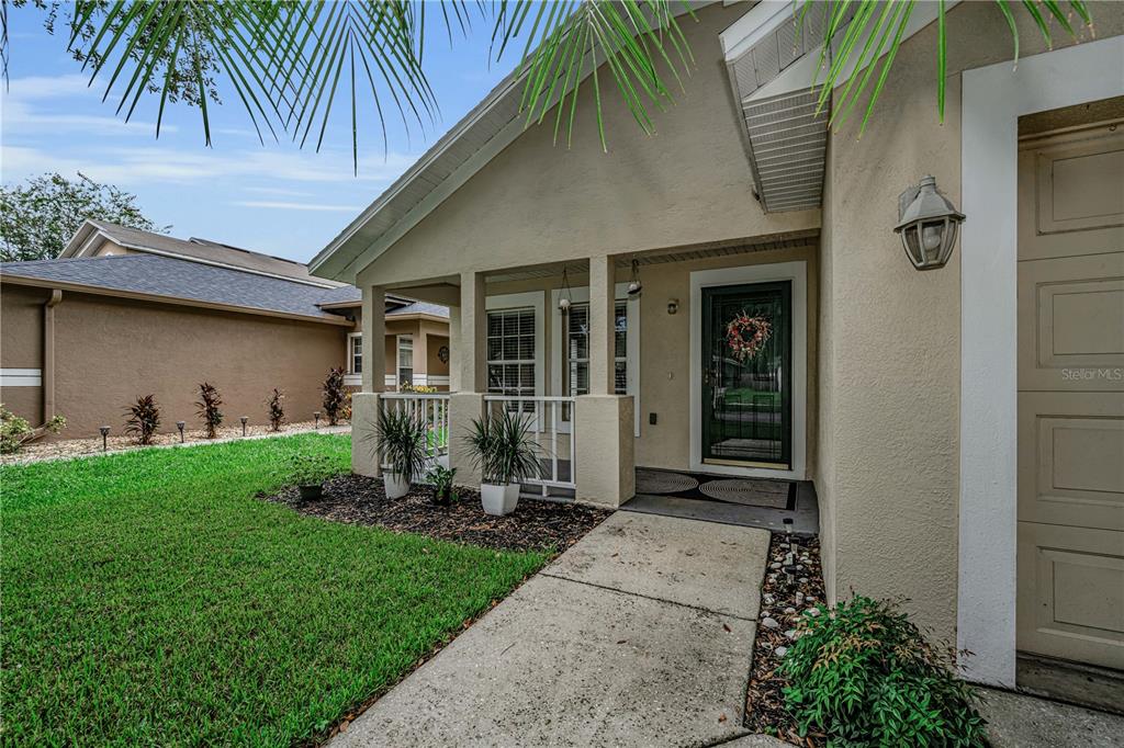A tan house exterior features a covered front porch, a concrete walkway, and a garage — 5229 MANGO FRUIT STREET, SEFFNER, FL