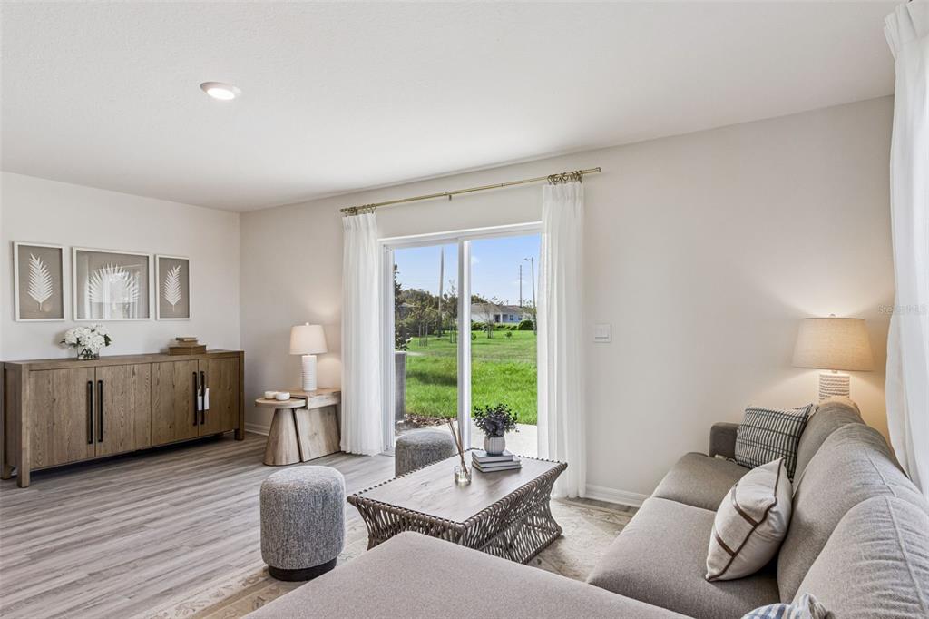 A living room features a gray sectional sofa, wood console, and sliding glass doors to outdoors — 4707 TONY STREET, LAKE WALES, FL