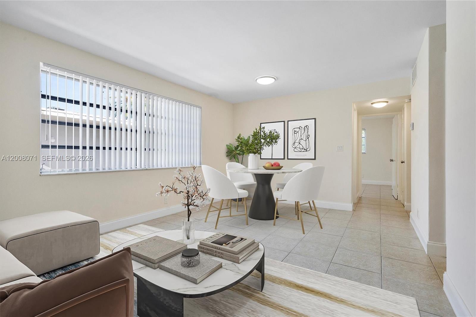 A dining area with a round table and chairs sits adjacent to a living room — 1715 N 16th Ave # 102, Hollywood FL 33020, HOLLYWOOD, FL