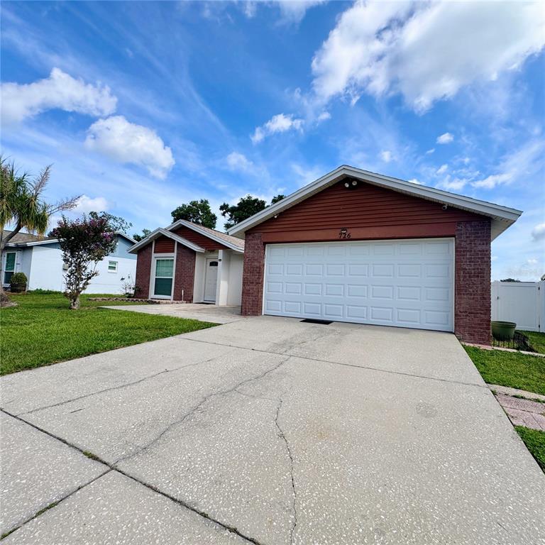A single-story house with a white garage door, red siding, and a brick facade — 726 STILLVIEW CIRCLE, BRANDON, FL