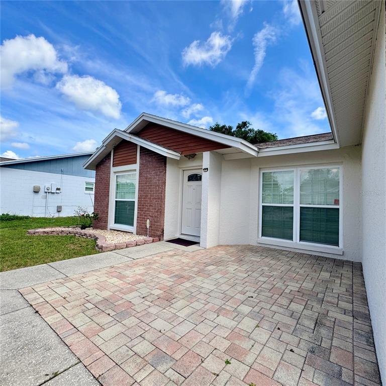 The exterior of a single-story house features a brick facade, white stucco, and paver patio — 726 STILLVIEW CIRCLE, BRANDON, FL