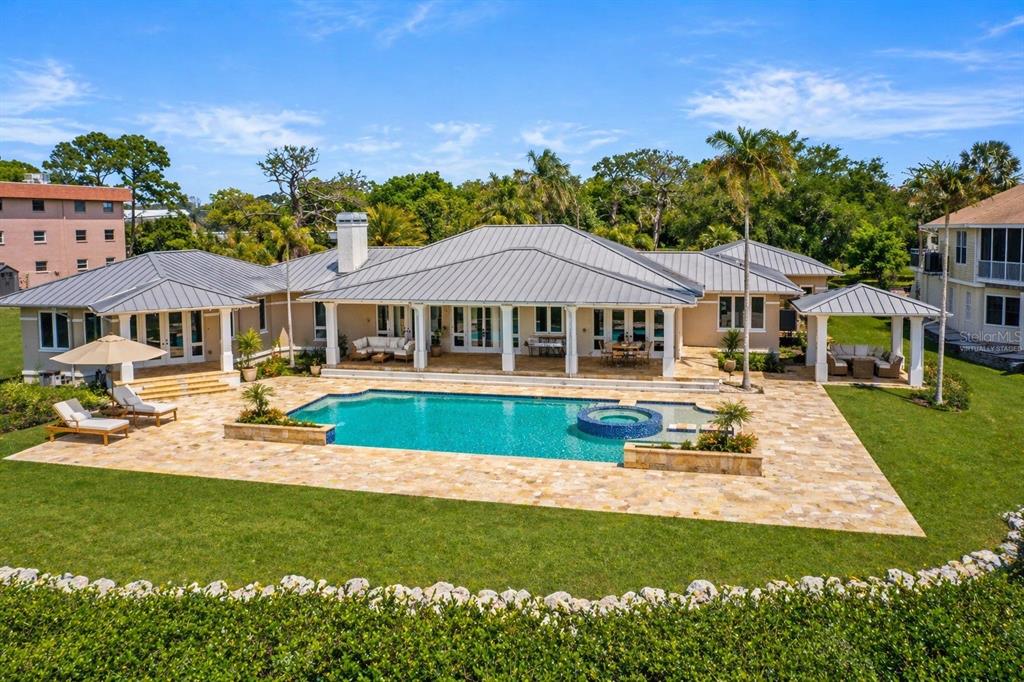 A single-story house with a metal roof, swimming pool, and stone patio in a backyard — 1721 GULF ROAD, TARPON SPRINGS, FL