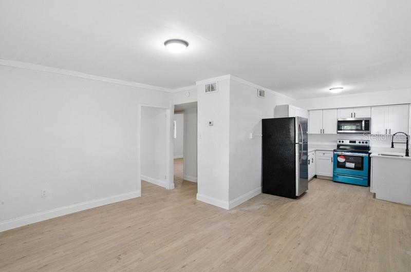 An open-concept kitchen and living area with light wood flooring and white walls — 2608 E CAYUGA STREET, TAMPA, FL
