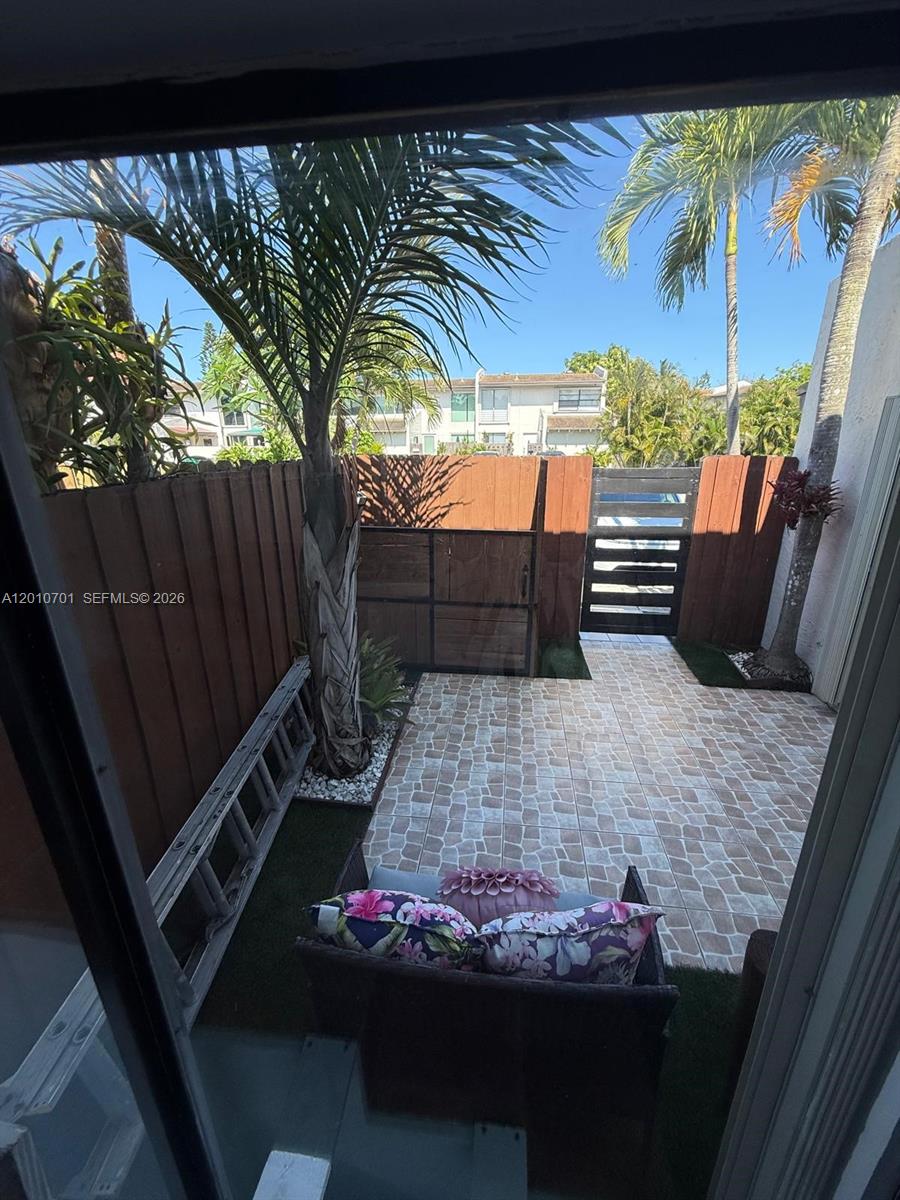 A small patio features tiled flooring, a palm tree, a wooden fence, and a gate — 6524 SW 114th Ave # 6524, Miami FL 33173, MIAMI, FL