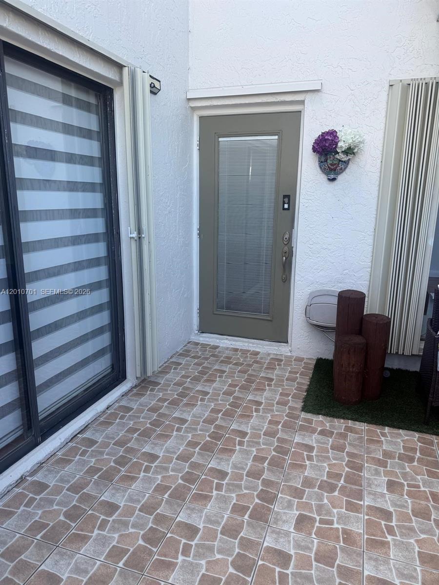 A tiled patio features a sliding glass door, a green entry door, and decorative wooden posts — 6524 SW 114th Ave # 6524, Miami FL 33173, MIAMI, FL