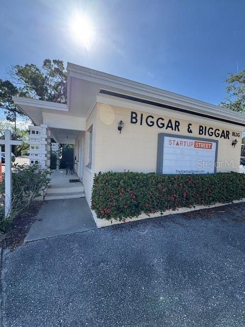 The exterior of a light-colored commercial building features a sign reading Biggar & Biggar — 3022 W SWANN AVENUE, TAMPA, FL