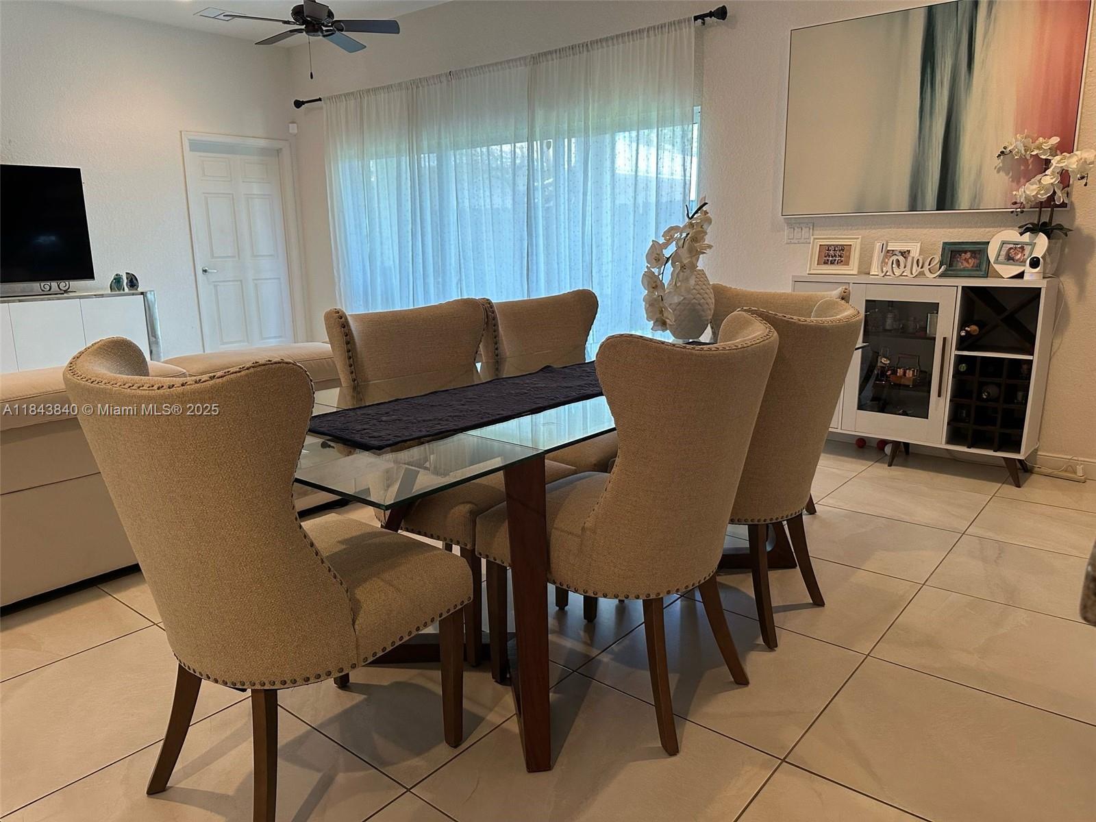 A dining area features a glass-topped table with six upholstered chairs on a tiled floor — 210 SW 4th St # 210, Dania Beach FL 33004, DANIA BEACH, FL