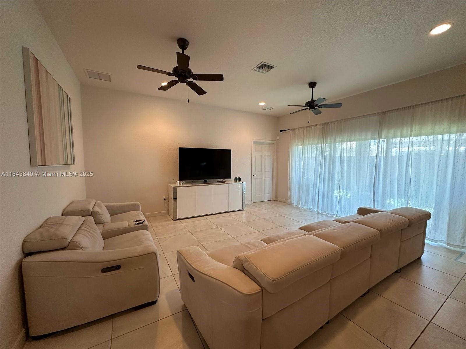 A living room features light-colored tile floors, two ceiling fans, and two beige sofas — 210 SW 4th St # 210, Dania Beach FL 33004, DANIA BEACH, FL