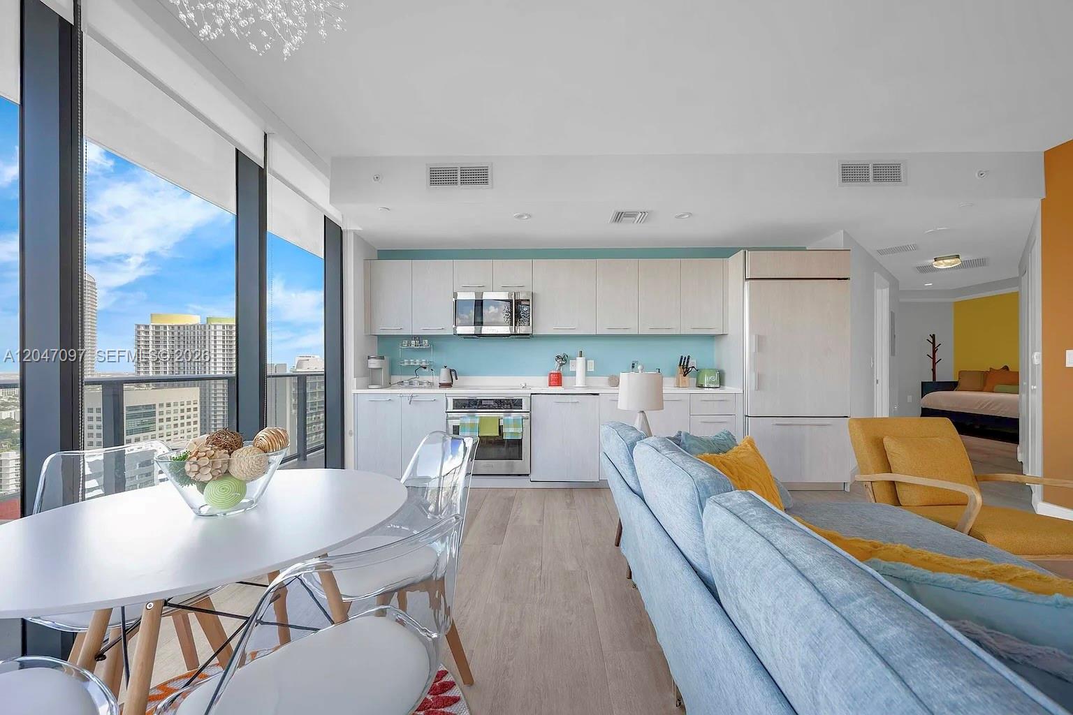 A modern apartment features an open-concept kitchen, dining area, and living room with floor-to-ceiling windows — 55 SW 9th St # 3306, Miami FL 33130, MIAMI, FL