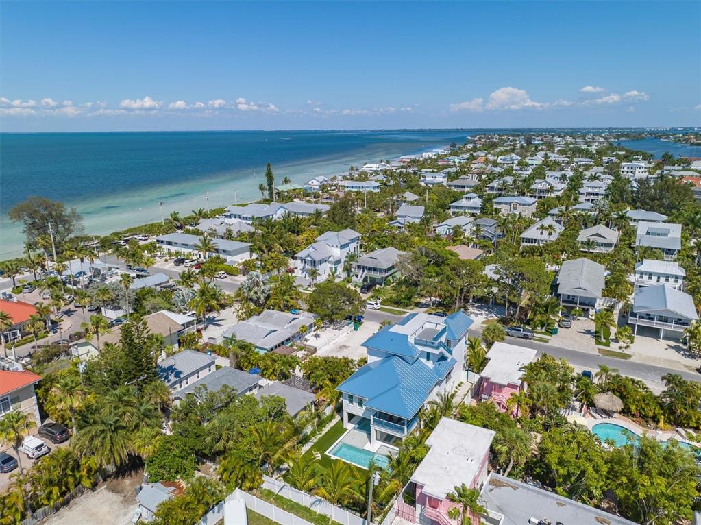 An aerial view shows a coastal neighborhood with houses, palm trees, and a swimming pool — 518 SPRING AVENUE, ANNA MARIA, FL